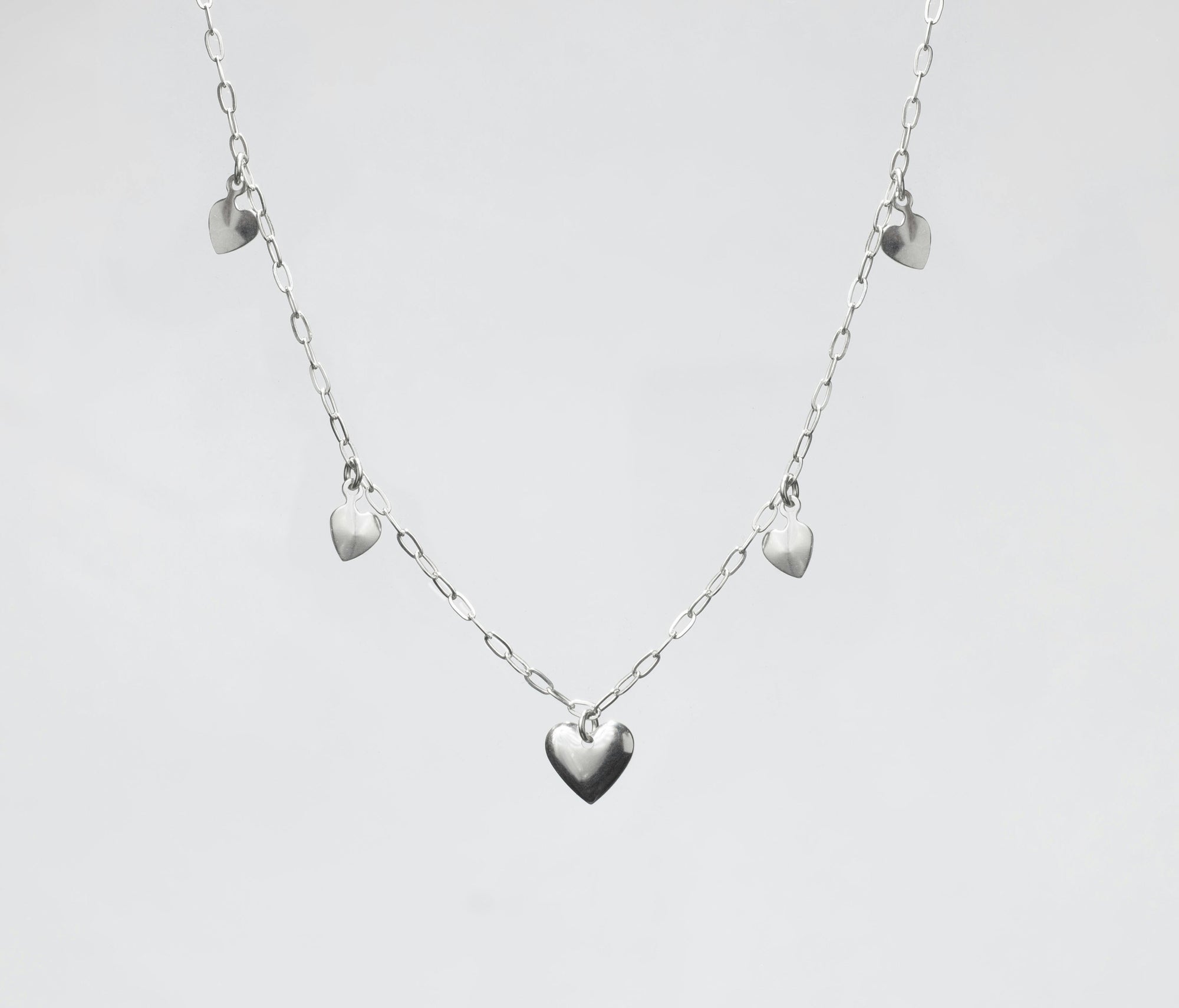 Silver necklace in bright plain background with hear shaped pendants
